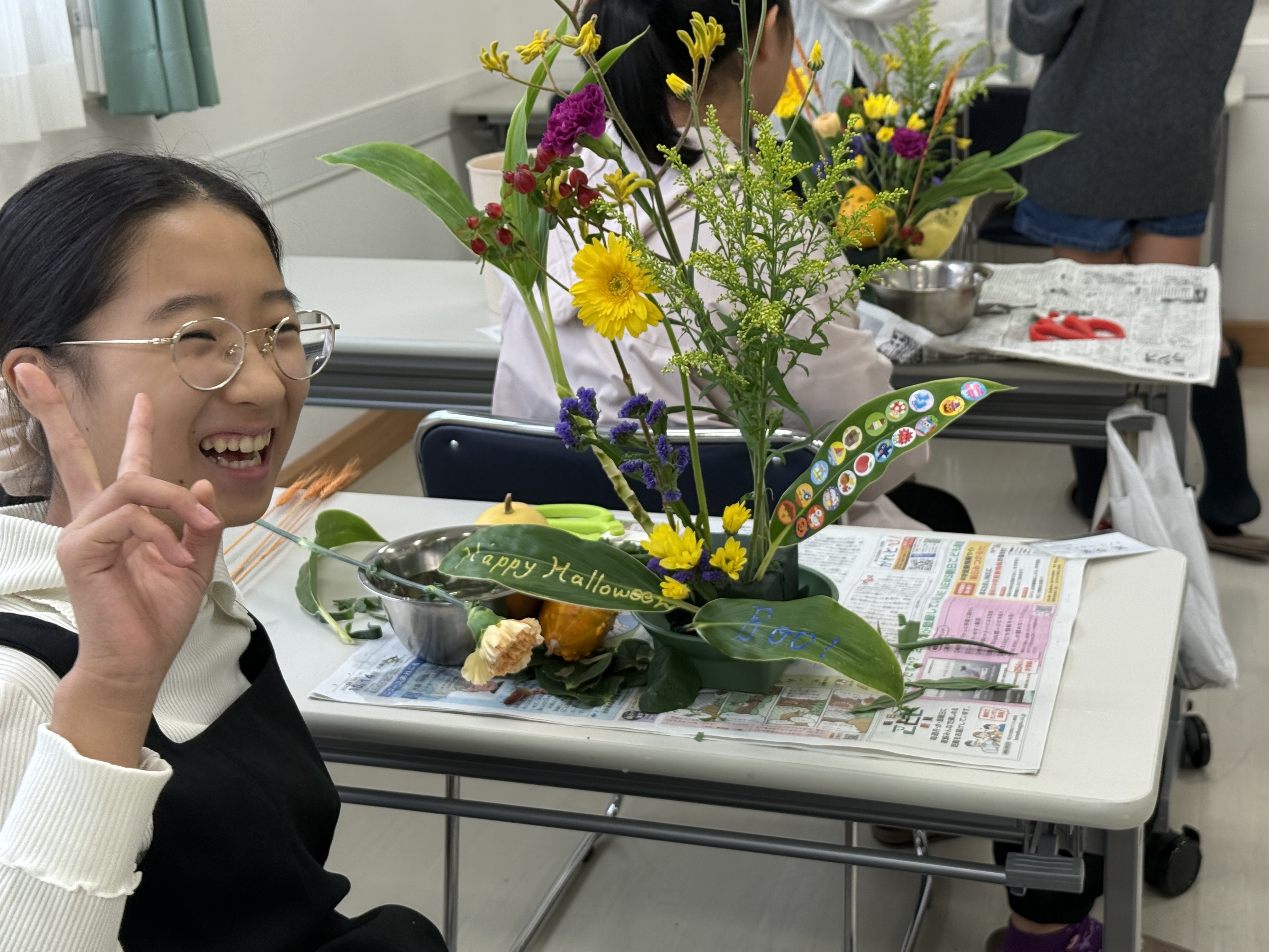 教室で生徒さんが笑顔で花を活ける風景